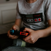 pessoa jogando nintendo switch usando uma camisa de um controle do NES